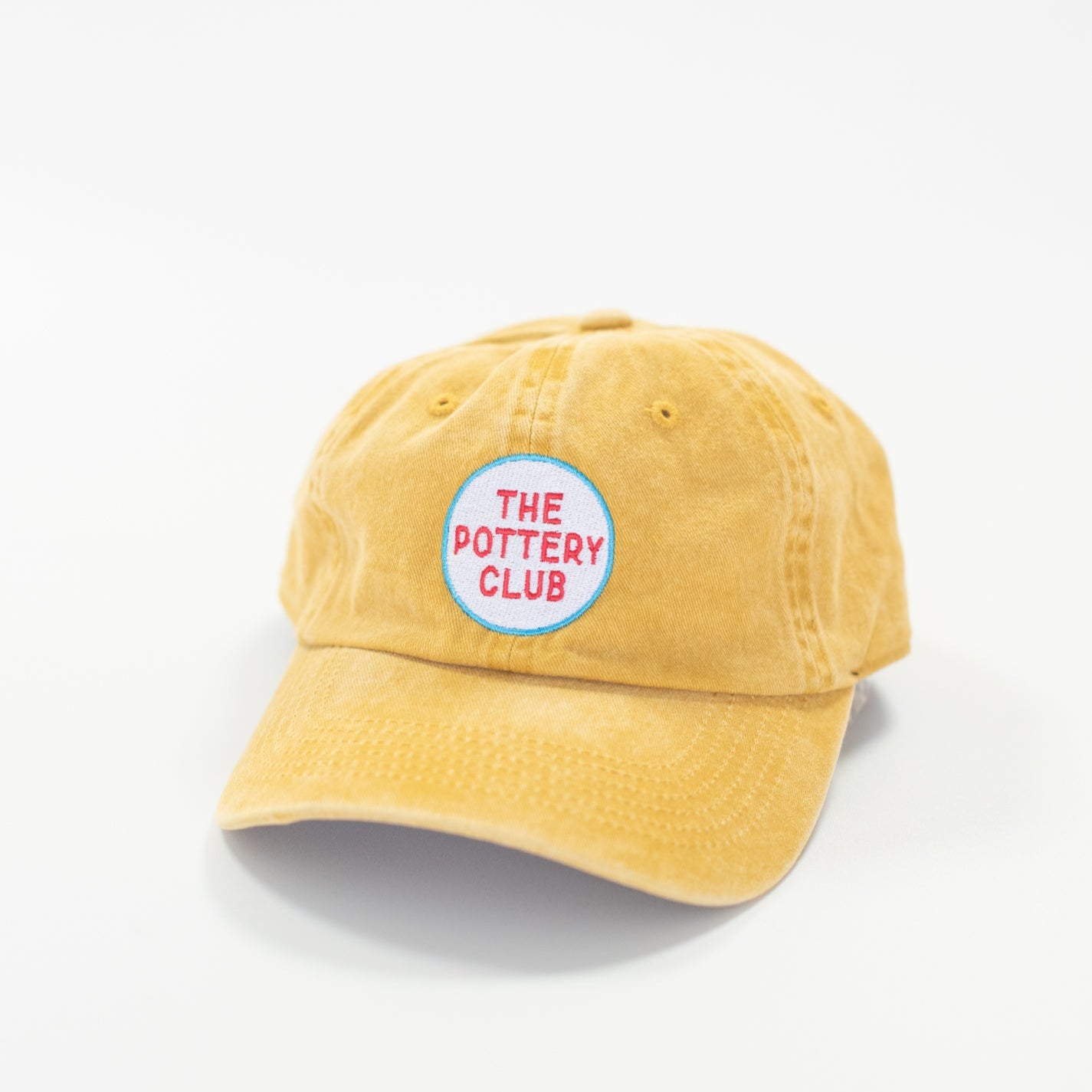Yellow cap with 'The Pottery Club' logo on a white background